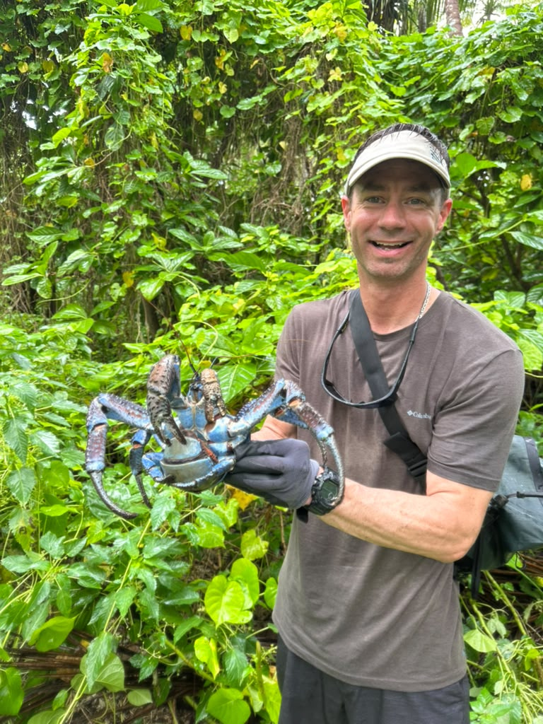Aaron Arrants, medic and safety officer, picks up a coconut crab during the second day on the island. Aaron Arrants, medic and safety officer, picks up a coconut crab during the second day on the island.